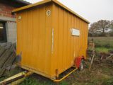 une petite remise jaune au milieu d'un champ