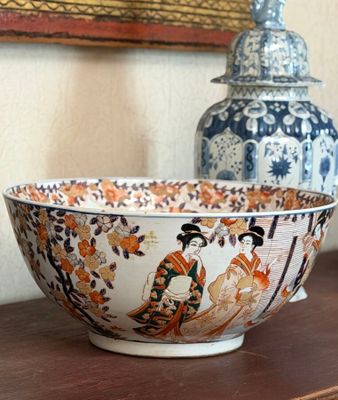 a bowl sitting on a table next to a vase on a shelf