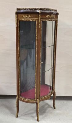une vitrine en verre avec un coussin rouge posé par terre