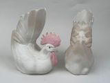 pair of white ceramic roosters with pink beaks on white background