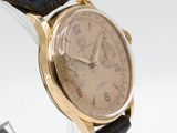a close up of a wrist watch with a gold case and black leather strap