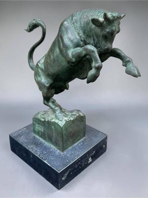 bronze sculpture of a bull leaping over a block on a marble base