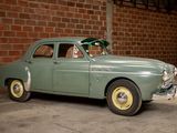 a green car parked in front of a brick wall