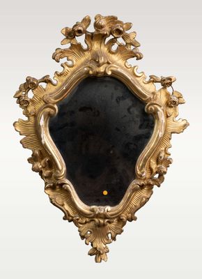 un miroir ancien à cadre doré, orné de fleurs et de feuilles sur fond blanc