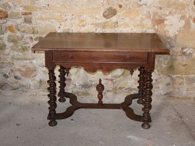 a small table with a drawer on it in front of a brick wall