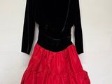 une robe rouge et noire suspendue à un cintre devant un mur blanc