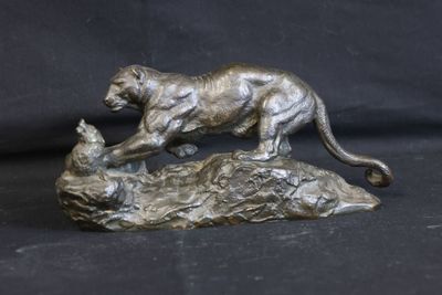 bronze statue of a cat and a cat laying on a rock