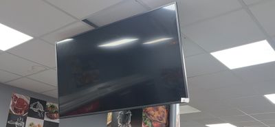a large flat screen tv hanging from the ceiling in a restaurant