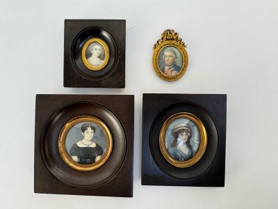 Trois portraits de femmes encadrés sont accrochés sur un mur blanc