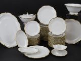 de nombreuses assiettes et bols blancs et dorés sur la table