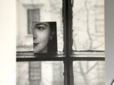 a black and white photo of a woman looking out of a window