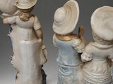 three ceramic figurines of children with hats on them