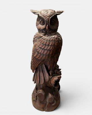 an owl statue sitting on top of a tree stump