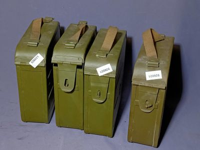 four army green metal boxes with tags on them sitting on a table