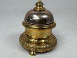 a silver and gold bell sitting on top of a table