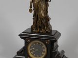 une statue de femme tenant une horloge sur une table