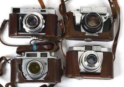 four cameras are lined up in a row on a white surface