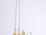 a gold coin necklace and a gold ring on a white surface