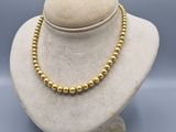a gold beaded necklace on a mannequin display