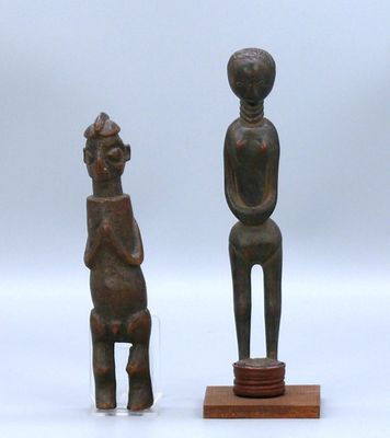 deux sculptures en bois représentant un homme et une femme assis sur un tabouret