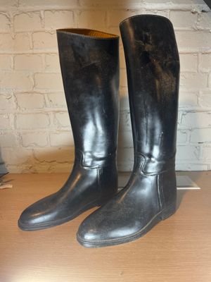 pair of black leather boots sitting on top of a wooden table