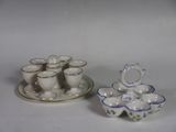 une assiette sur laquelle sont posées des tasses et des soucoupes, à côté d'une autre assiette sur laquelle sont posées des tasses et des soucoupes