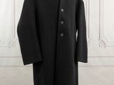 a black coat on a mannequin stand in front of a white wall