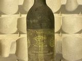 une bouteille de vin posée sur une table devant un mur de tasses