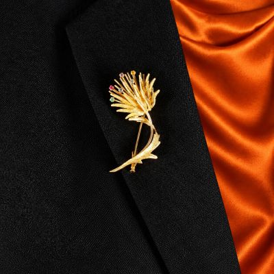 a close up of a gold flower brooch on a black suit
