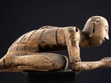 une image représentant une statue en bois d'un homme à genoux sur un socle