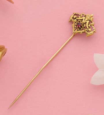 une image représentant une broche en or ornée d'une fleur sur fond rose