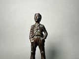 bronze figurine of a man standing on a base with his hands on his hips