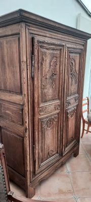 une armoire en bois, avec une chaise et une table devant