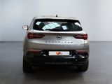 the back of a silver car in a room with a white wall