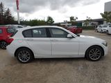a white bmw car parked in a lot with other cars