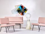 three chairs and a table in a room with a painting on the wall