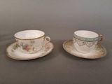 two cups and saucers sitting on a table with a gray background
