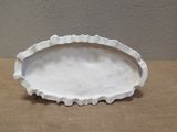 a white plate with a ruffled edge on a table