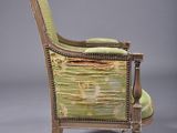 an old chair with a green upholstered seat and a wooden frame