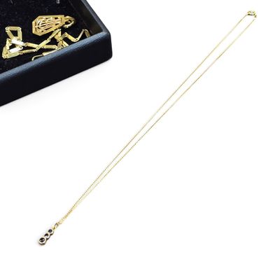 Collier avec un crâne et des os croisés plaqué or, présenté dans un coffret en velours noir