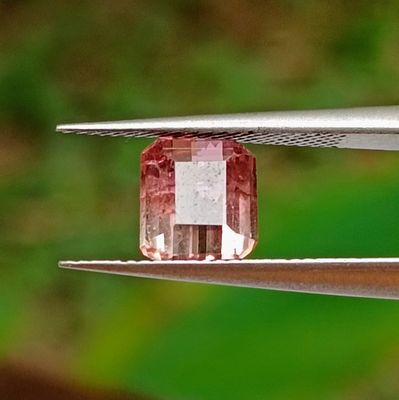 a close up of a pink diamond being cut by a pair of pliers