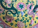 a yellow plate with a dragon and flowers on it