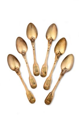 six gold spoons are arranged in a circle on a white surface