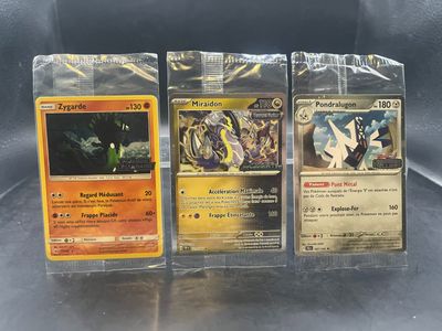 Trois cartes Pokémon sont posées sur une table