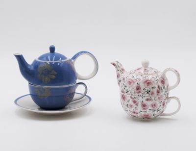 two teapots and a saucer sitting on a saucer