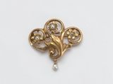 a close up of a gold brooch with pearls on it