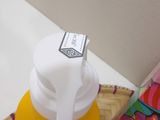 a yellow cup with a white lid sitting on a table next to a book