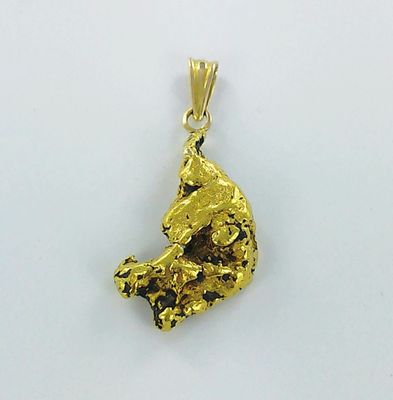 gros plan d'un pendentif en or sur une surface blanche
