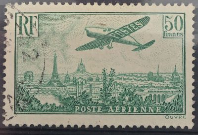 un vieux timbre représentant un avion survolant une ville