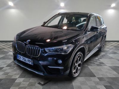 the bmw x1 is parked in a large room with a checkered floor
